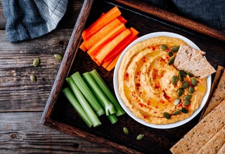 A dish with hummus and chopped cucumber and carrots