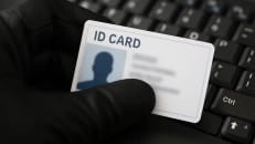 a person holding a id card in front of a keyboard