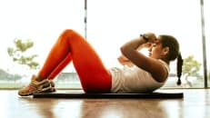 A good looking woman performs crunches on the floor to boost her metabolism