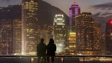 A silhouette of a couple in front of the skyline of a major city 