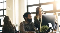 Two employees of a small business look at a computer screen discussing a website builder