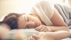 A young woman is a asleep and dreaming.