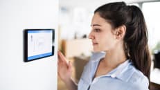 A young woman monitors her home's energy usage on a smart home screen