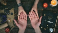 A psychic performs a palm reading on a client.
