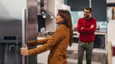 Young couple, satisfied customers choosing fridges in appliances store.