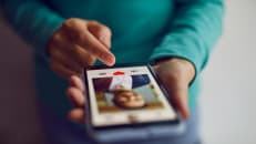 Dating online. Mobile phone in hands of woman who scrolling through profiles of men and pressing red heart button with her finger.