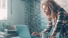 Modern woman at home using laptop on the table with wireless internet connection. 