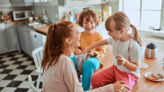 Young mother and her kids having breakfast together and being messy in the kitchen