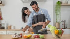 Happy couple in love cooking in the kitchen counter at home and hugging