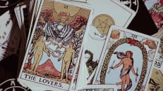 A tarot deck lies on a table showing the "The Lovers" card
