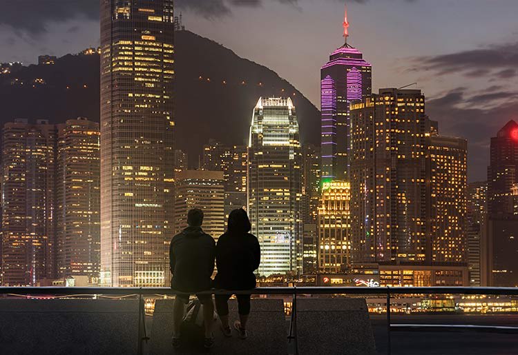 A silhouette of a couple in front of the skyline of a major city 