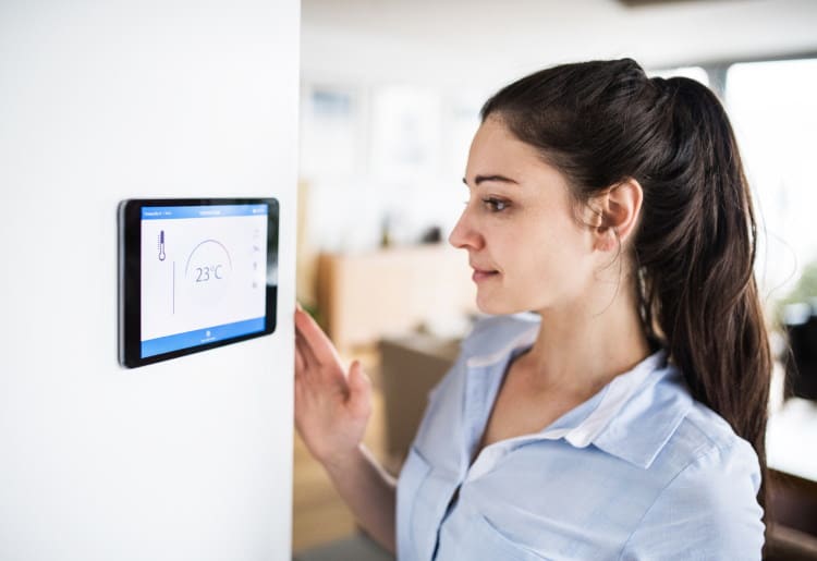 A young woman monitors her home's energy usage on a smart home screen
