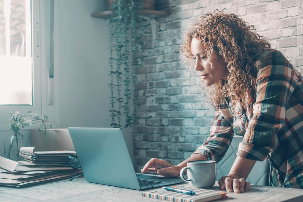 Modern woman at home using laptop on the table with wireless internet connection. 
