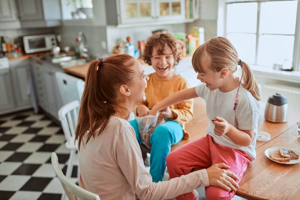 Young mother and her kids having breakfast together and being messy in the kitchen